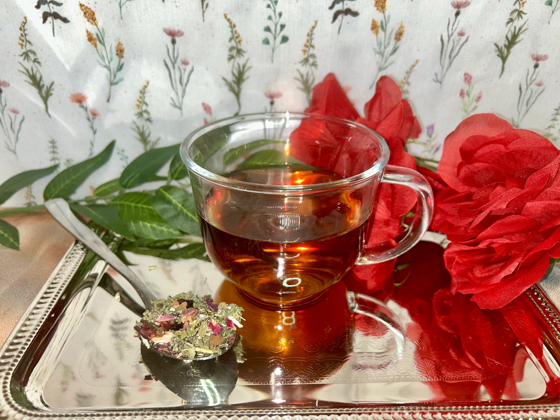 Glass tea cup of calming herbal tea and a teaspoon of dried herbs
