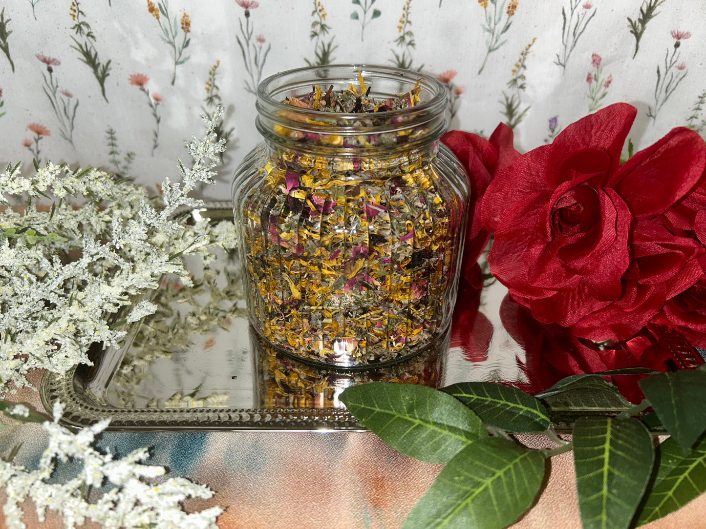 Glass jar of dried organic tea blend of of red raspberry leaf, lavender, plantain leaf, hibiscus, rose, mugwort, and calendula for vaginal steaming